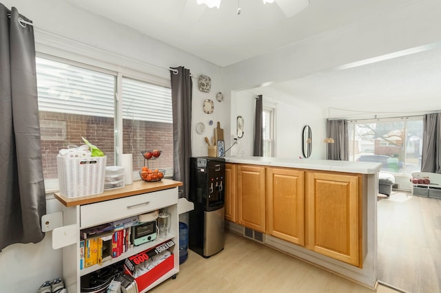 kitchen featuring light wood finished floors, a peninsula, visible vents, ceiling fan, and light countertops