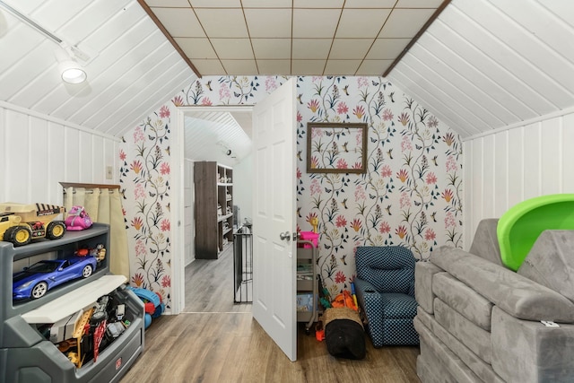 additional living space featuring wallpapered walls, vaulted ceiling, and wood finished floors