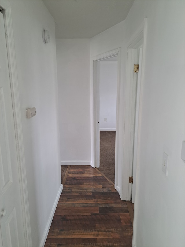 corridor with dark wood-style floors and baseboards