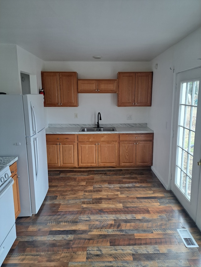 kitchen with visible vents, a sink, dark wood finished floors, brown cabinets, and range