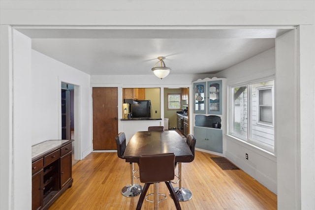 dining room with baseboards, visible vents, and light wood finished floors