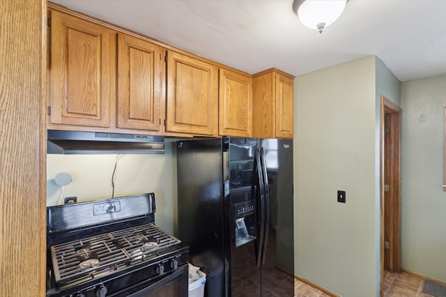 kitchen with brown cabinetry, black refrigerator with ice dispenser, under cabinet range hood, and range with gas cooktop