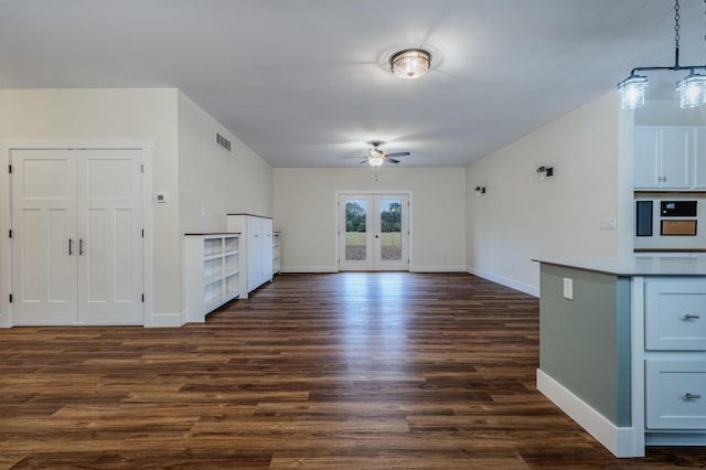 interior space with pendant lighting, a ceiling fan, open floor plan, dark wood finished floors, and baseboards