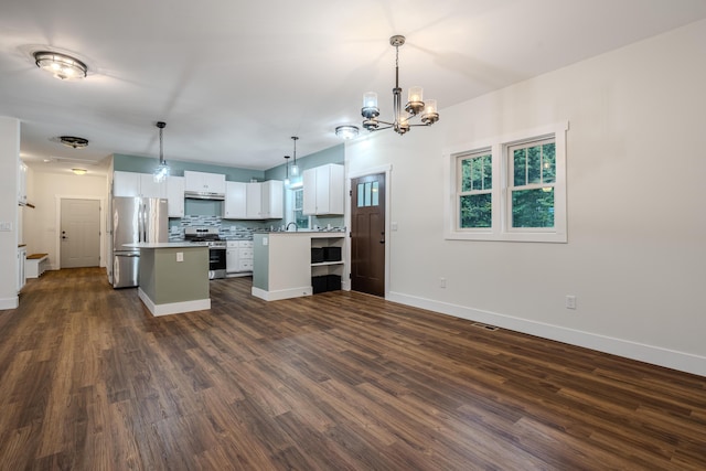 kitchen featuring backsplash, dark wood finished floors, open floor plan, an inviting chandelier, and stainless steel appliances