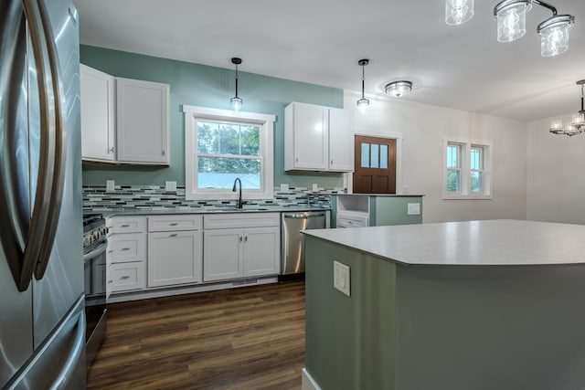 kitchen with a sink, decorative backsplash, dark wood-type flooring, stainless steel appliances, and a chandelier