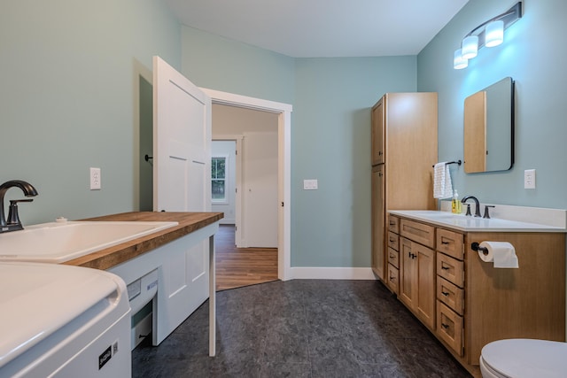 bathroom with washer / clothes dryer, toilet, vanity, and baseboards
