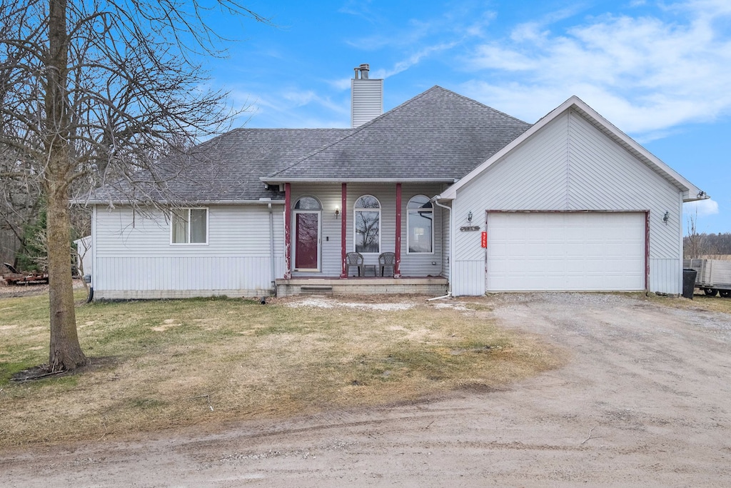 ranch-style house with driveway, covered porch, an attached garage, a shingled roof, and a chimney