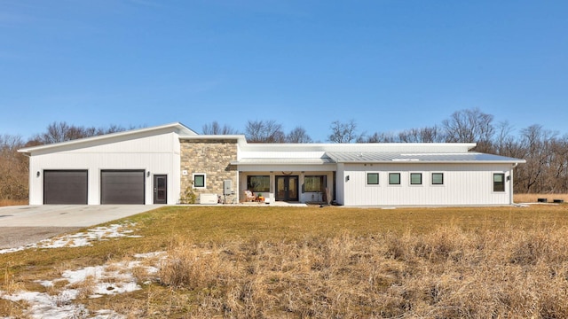 5595 Riverview Dr, Bridgeport, MI 48722 - view of front of property featuring stone siding, an attached garage, metal roof, and concrete driveway