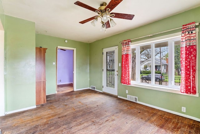 unfurnished room with baseboards, ceiling fan, wood finished floors, and visible vents