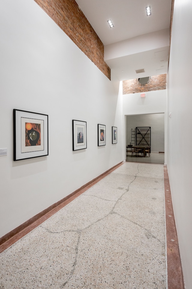 interior space with visible vents, speckled floor, baseboards, and a towering ceiling