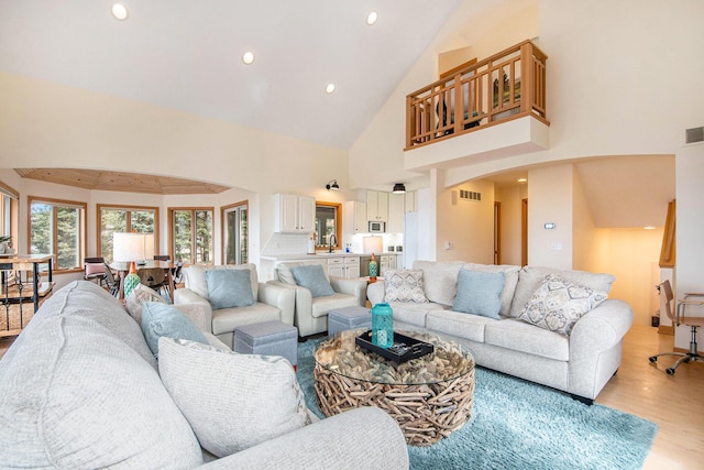19148 Maiden Ln, Spring Lake, MI 49456 - living room with high vaulted ceiling, light wood-style floors, arched walkways, and recessed lighting