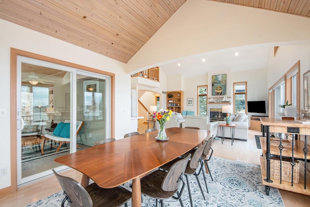 19148 Maiden Ln, Spring Lake, MI 49456 - dining space featuring light wood finished floors, a glass covered fireplace, arched walkways, high vaulted ceiling, and recessed lighting