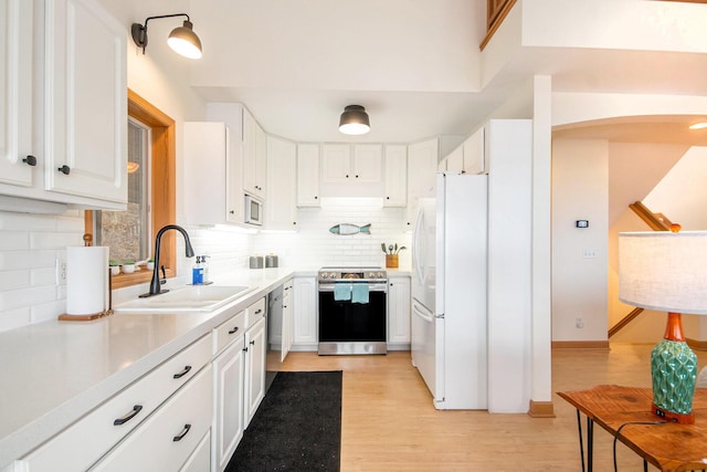 19148 Maiden Ln, Spring Lake, MI 49456 - kitchen with stainless steel appliances, decorative backsplash, white cabinets, light wood-style flooring, and light countertops