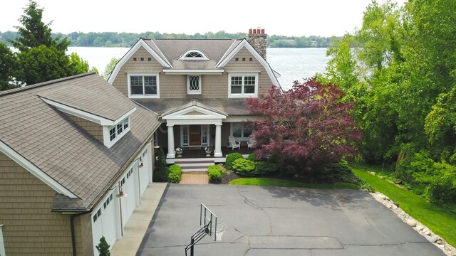 2634 Reeds Lake Ct SE, East Grand Rapids, MI 49506 - view of front of house with a water view, a porch, driveway, a garage, and a chimney