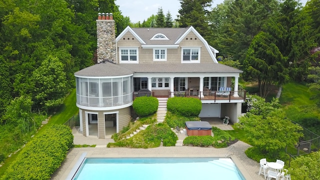 2634 Reeds Lake Ct SE, East Grand Rapids, MI 49506 - rear view of property featuring a hot tub, a patio, an outdoor pool, and a sunroom