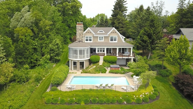 2634 Reeds Lake Ct SE, East Grand Rapids, MI 49506 - rear view of house with a sunroom, a hot tub, a chimney, an outdoor pool, and a wooden deck
