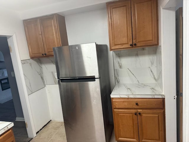 18308 Littlefield St, Detroit, MI 48235 - kitchen featuring backsplash, brown cabinetry, and freestanding refrigerator