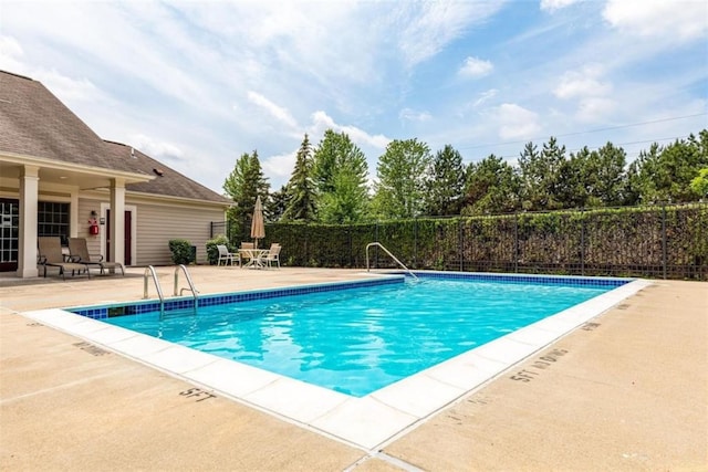 community pool with a patio area and fence