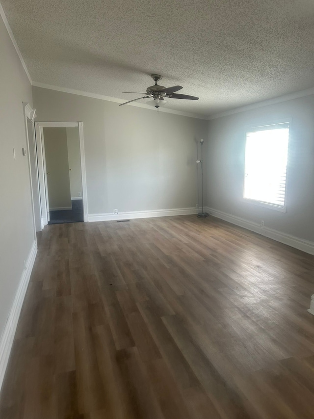 spare room featuring dark wood finished floors, a textured ceiling, ornamental molding, and a ceiling fan