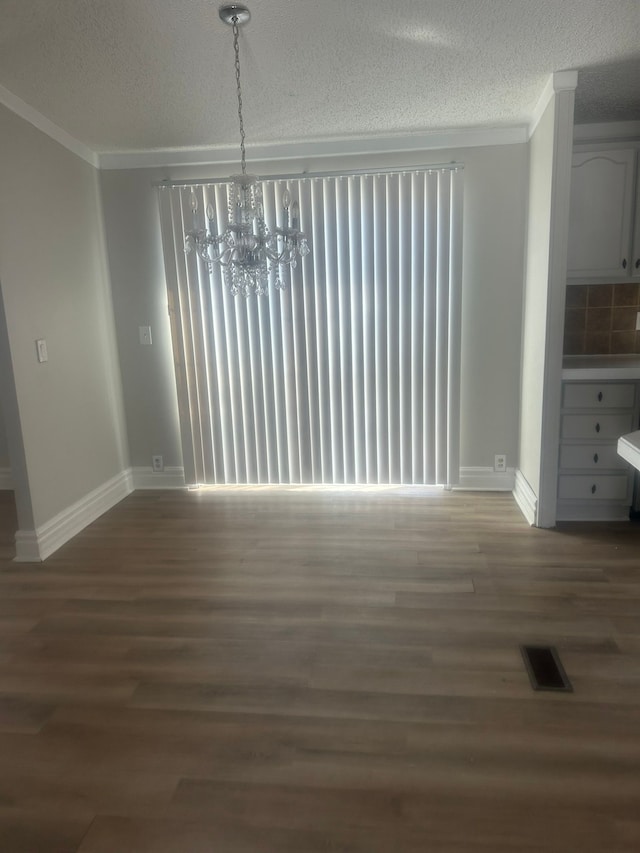 unfurnished dining area with ornamental molding, visible vents, an inviting chandelier, and wood finished floors