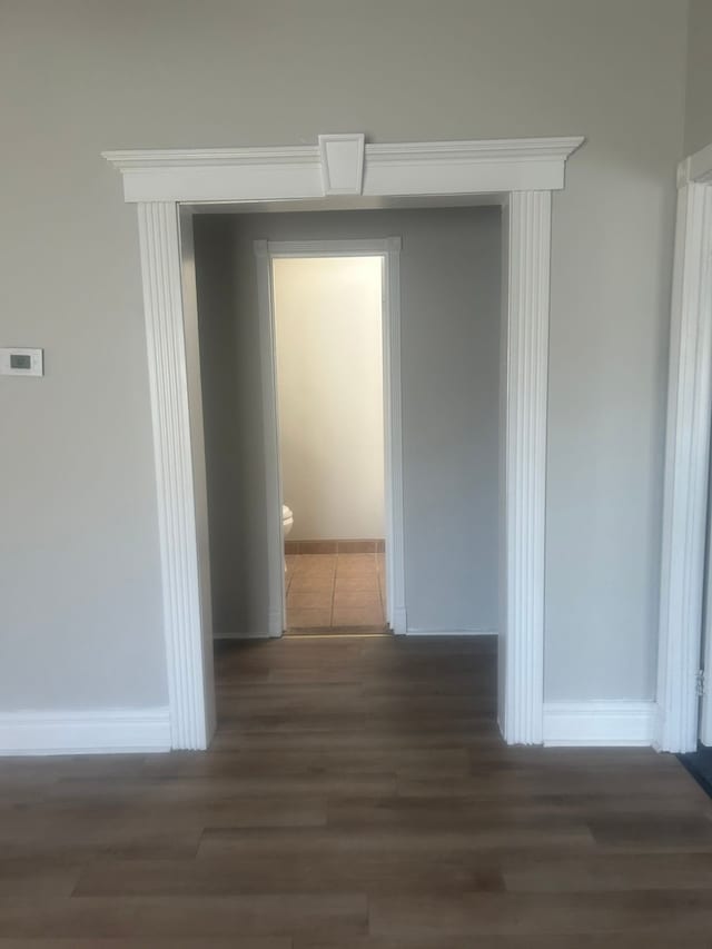 corridor with baseboards and wood finished floors