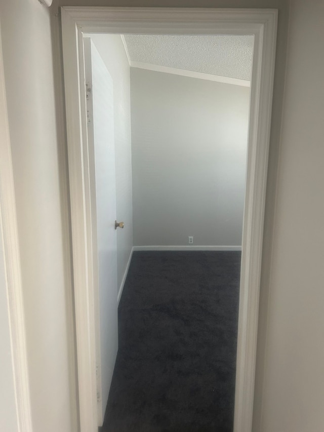 hall featuring baseboards, carpet floors, ornamental molding, and a textured ceiling
