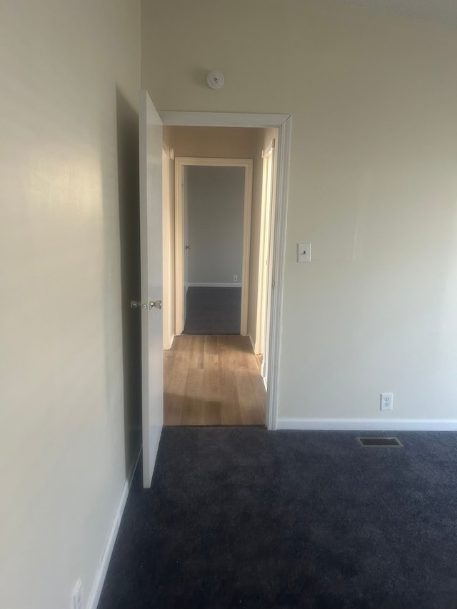 hallway with carpet, baseboards, and visible vents