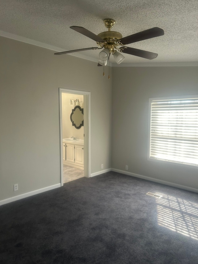 spare room with a textured ceiling, baseboards, carpet flooring, and a ceiling fan