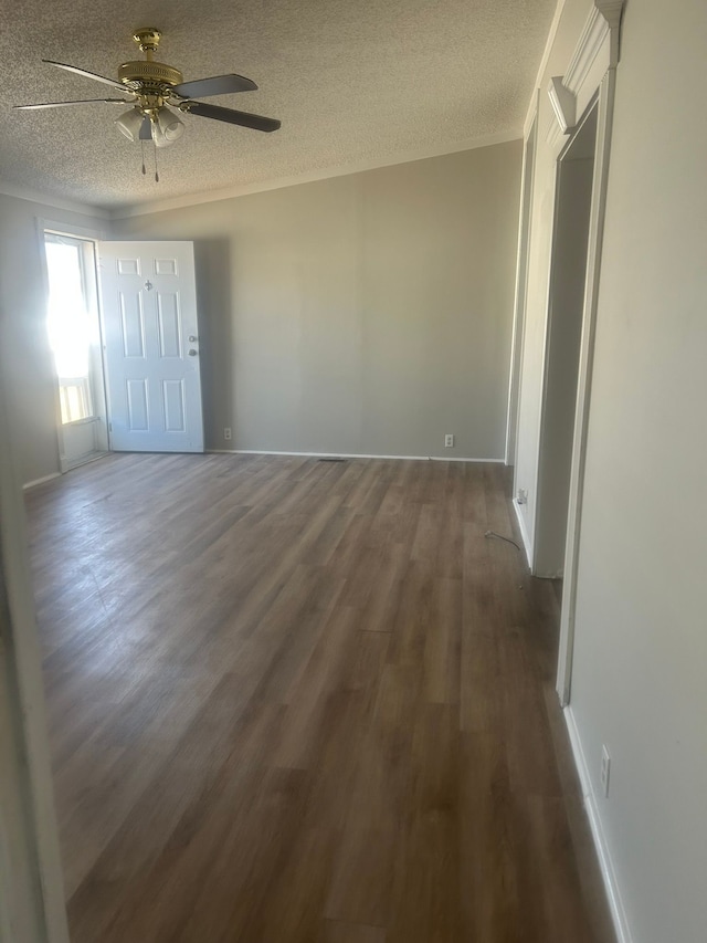 unfurnished room with a textured ceiling, dark wood-style flooring, ornamental molding, and a ceiling fan