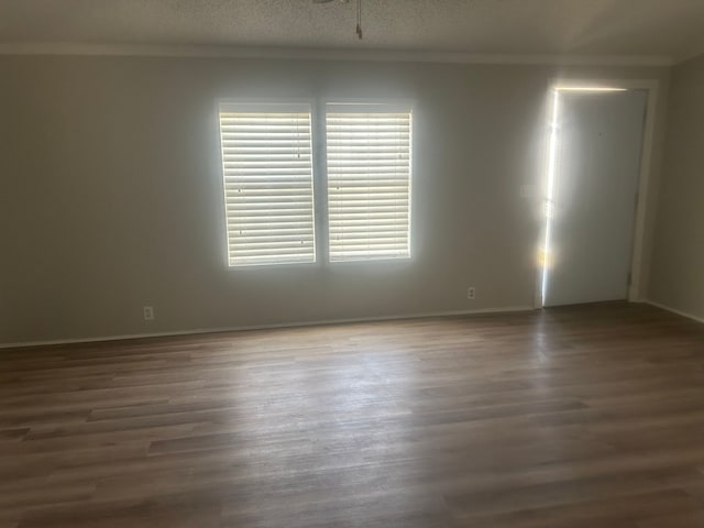spare room with a textured ceiling, wood finished floors, and ornamental molding