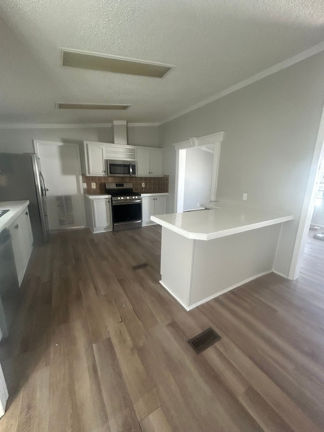 kitchen featuring crown molding, stainless steel appliances, visible vents, white cabinets, and dark wood-type flooring