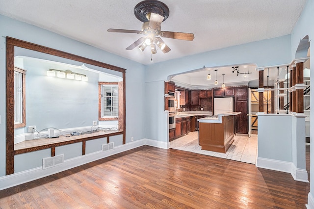 kitchen featuring visible vents, freestanding refrigerator, light wood-style floors, light countertops, and ceiling fan