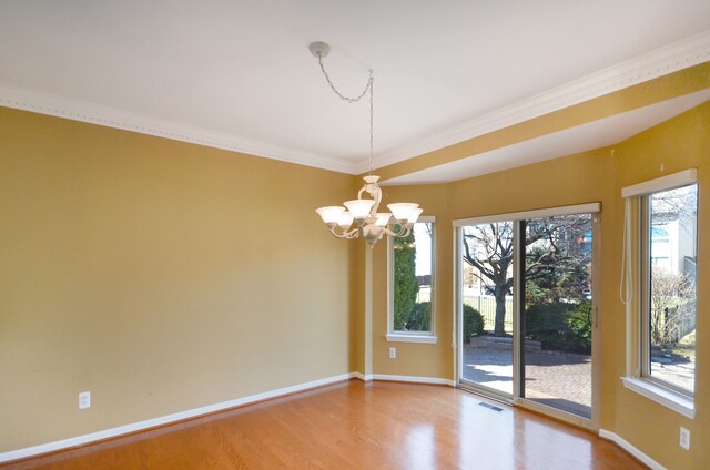 unfurnished room with crown molding, wood finished floors, baseboards, visible vents, and an inviting chandelier