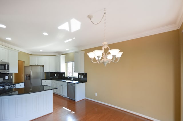 kitchen with a chandelier, dark countertops, tasteful backsplash, appliances with stainless steel finishes, and a sink