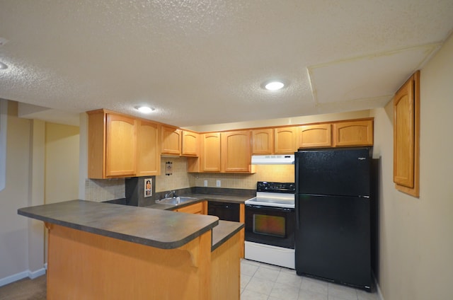 kitchen with freestanding refrigerator, a peninsula, under cabinet range hood, electric stove, and dark countertops