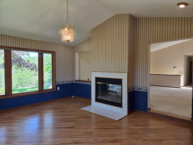 3380 Watersedge Dr, Brighton, MI 48114 - unfurnished living room with vaulted ceiling, wallpapered walls, a tile fireplace, wood finished floors, and baseboards