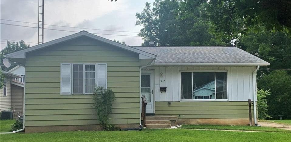 bungalow featuring a shingled roof, cooling unit, and a front yard
