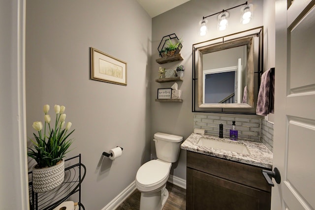 half bath featuring wood finished floors, decorative backsplash, toilet, vanity, and baseboards