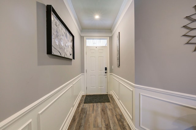 doorway to outside with wainscoting, ornamental molding, dark wood-style flooring, and a decorative wall