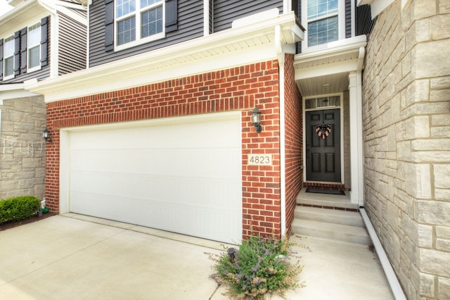 view of exterior entry featuring brick siding, an attached garage, and stone siding