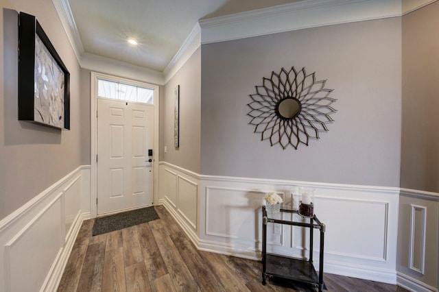 entryway with crown molding, a wainscoted wall, a decorative wall, and dark wood-type flooring