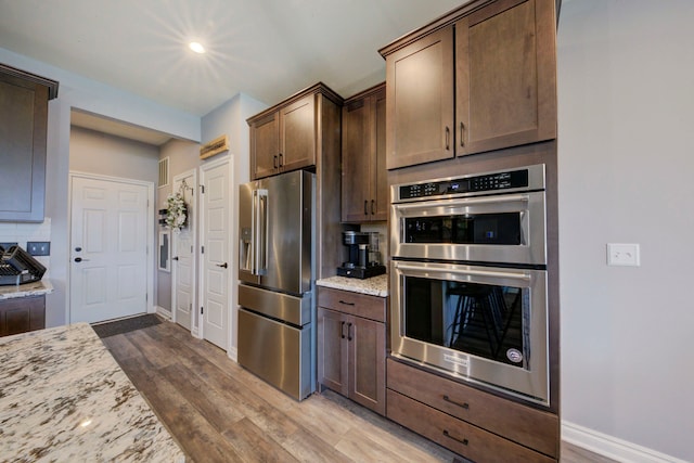 kitchen featuring baseboards, light stone countertops, stainless steel appliances, and dark wood-type flooring