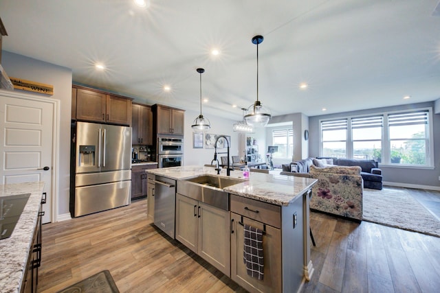 kitchen with a sink, appliances with stainless steel finishes, open floor plan, and plenty of natural light