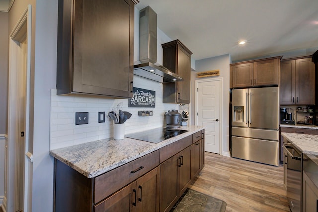 kitchen with light wood-style flooring, decorative backsplash, stainless steel fridge, black electric cooktop, and wall chimney exhaust hood
