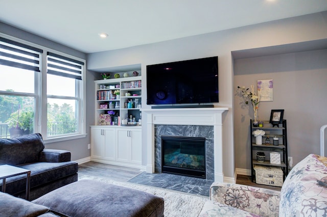 living room with wood finished floors, recessed lighting, a high end fireplace, and baseboards