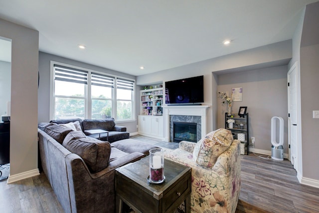 living area with a fireplace, recessed lighting, wood finished floors, and baseboards