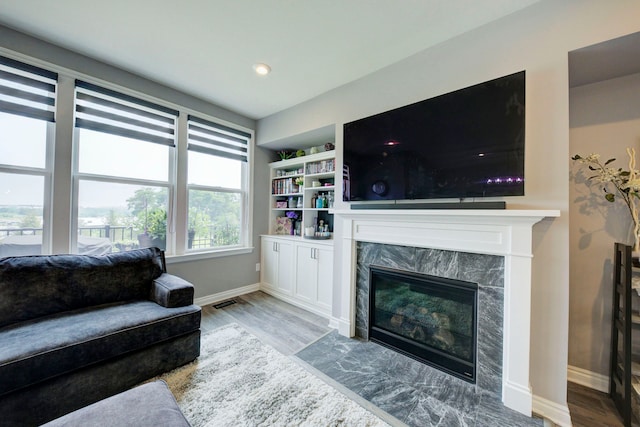 living area featuring recessed lighting, wood finished floors, a high end fireplace, baseboards, and visible vents