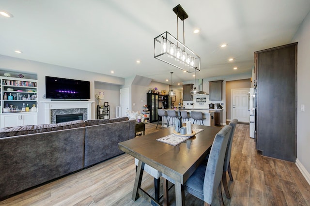 dining area with a fireplace, wood finished floors, and recessed lighting