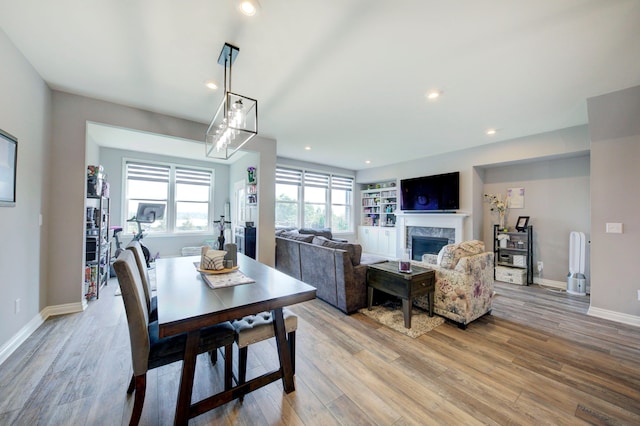 dining space with recessed lighting, a premium fireplace, and light wood-style flooring