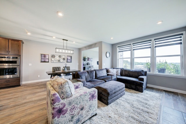 living room with visible vents, light wood-type flooring, recessed lighting, and baseboards